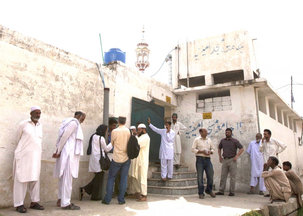 Members of the media and residents gather outside a mosque on August 23 near the locked family house of Rimsha Masih, a Pakistani Christian girl accused of blasphemy, on the outskirts of Islamabad.