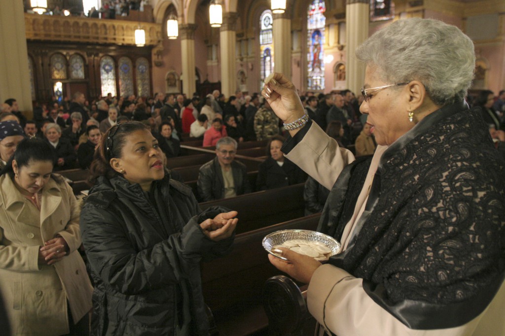 A eucharistic minister distributes Communion, all Catholics prepare to celebrate the 50th anniversary of the Second Vatican Council, all church members need to make a renewed effort to ensure laypeople are aware of their responsibility for the church.
