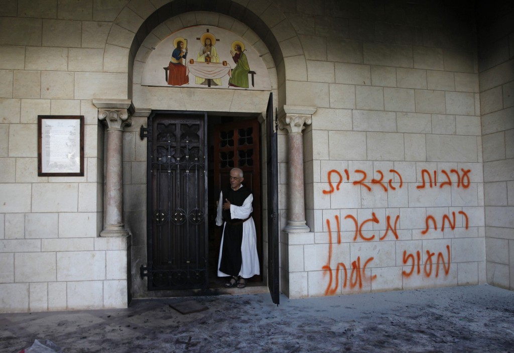 A monk stands next to graffiti sprayed on a wall at the entrance to the vandalised Trappist monastery outside Jerusalem on September 4. 
