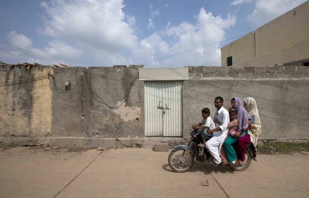 A family rides past the locked house of Rimsha Masih, a Pakistani Christian girl accused of blasphemy, in Islamabad.