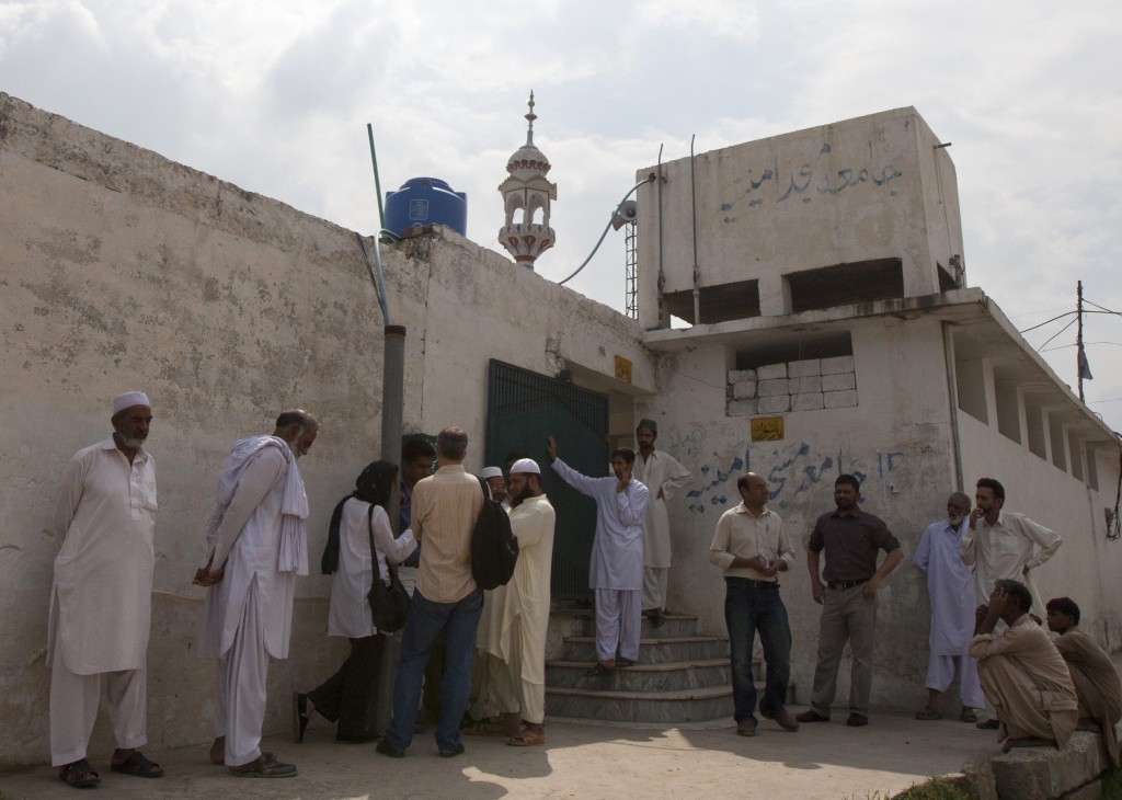Members of the media and residents gather outside a mosque Aug. 23 near the locked family house of Rimsha Masih, a Pakistani Christian girl accused of blasphemy, on the outskirts of Islamabad in August this year..