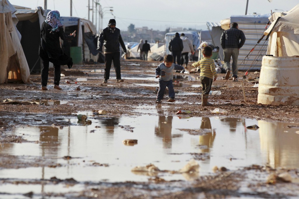 Young Syrian refugees stand outside their tents after heavy rain Jan. 10 at the Zaatari refugee camp in the Jordanian border town of Mafraq. PHOTO: CNS/Muhammad Hamed, Reuters