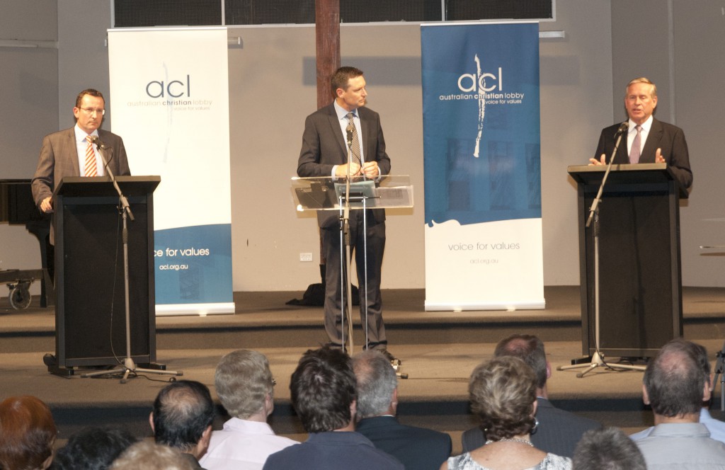 As moderator Lyle Shelton looks on, WA Premier Colin Barnett addresses voters at the information evening convened by the Australian Christian Lobby at the Mt Pleasant Baptist Community Centre on February 26 while Opposition Leader Mark McGowan, at left, waits his turn to speak. Both candidates faced a range of questions, including from Perth Bishop Donald Sproxton on housing and from CYM director Anita Parker on abortion. PHOTO: Matthew Biddle