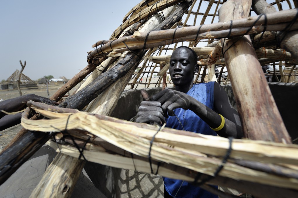 Deng Agany works on the framework of a thatched-roof hut in late February in Agok, a town in the contested Abyei region where tens of thousands of people fled in 2011 after an attack by soldiers and militias from Sudan. PHOTO: CNS/Paul Jeffrey