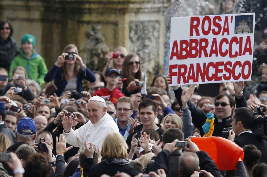A priest holds a sign in Italian saying "Rosa embraces Francesco" as Pope Francis arrives to lead his general audience in St. Peter's Square at the Vatican April 3. Rosa is a city in Italy. PHOTO: CNS/Paul Haring 