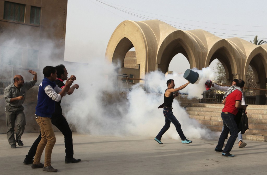A man uses a bucket to put out a tear gas canister as Egyptians run inside St. Mark Coptic Orthodox Cathedral in Cairo April 7, while police fire tear gas during clashes with Muslims. PHOTO: CNS/Asmaa Waguih, Reuters