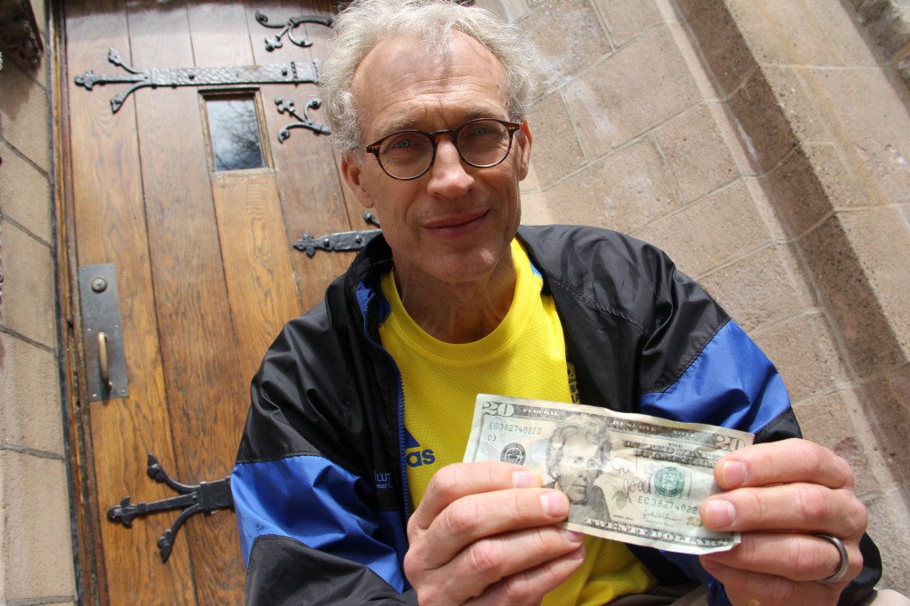 Dr. Joseph Stavas, 58, holds up a $20 bill April 16, with the words "God is Good" written on it. He found it crumpled in his running shorts the day after the deadly explosions at the Boston Marathon. Stavas, who ran the marathon with his physician-daughter, reflects on her heroism in helping victims, talks about the need for prayer and the inspiration from the Lord to get through it. PHOTO: CNS/Christopher S. Pineo, The Pilot