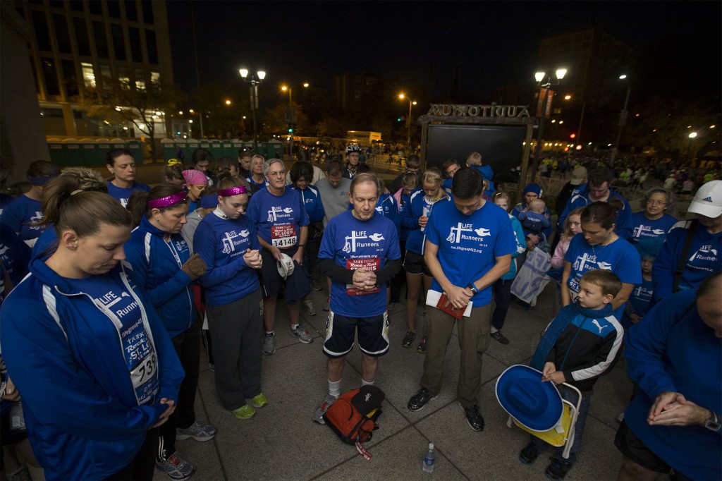 Bishop Thomas J. Paprocki of Springfield, Ill., center, leads a group of Life Runners in prayer in 2012 before a marathon in St. Louis. Life Runners, a pro-life group whose members participate in races all over the U.S., had at least two teammates in the Boston Marathon. When news about the bombings broke, the team confirmed their members were OK, then used a Facebook posting to call members around the U.S. to pray for the victims in Boston. PHOTO: CNS/Jerry Naunheim Jr., St. Louis Review