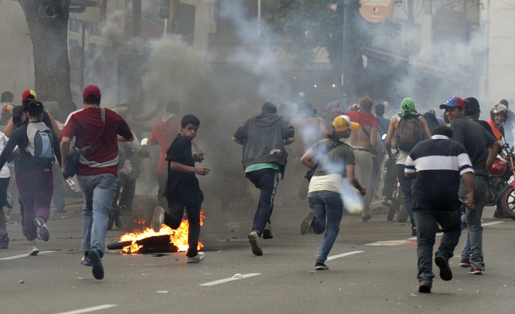 Supporters of opposition leader Henrique Capriles run away from tear gas fired by riot police in Caracas, Venezuela, April 15, as they demonstrated for a recount of the votes in the presidential election. Pope Francis called on Venezuela's political leaders to resolve their differences through respectful dialogue and urged the nation's people to reject all forms of violence as the country seeks to move ahead. PHOTO: CNS/Christian Veron, Reuters