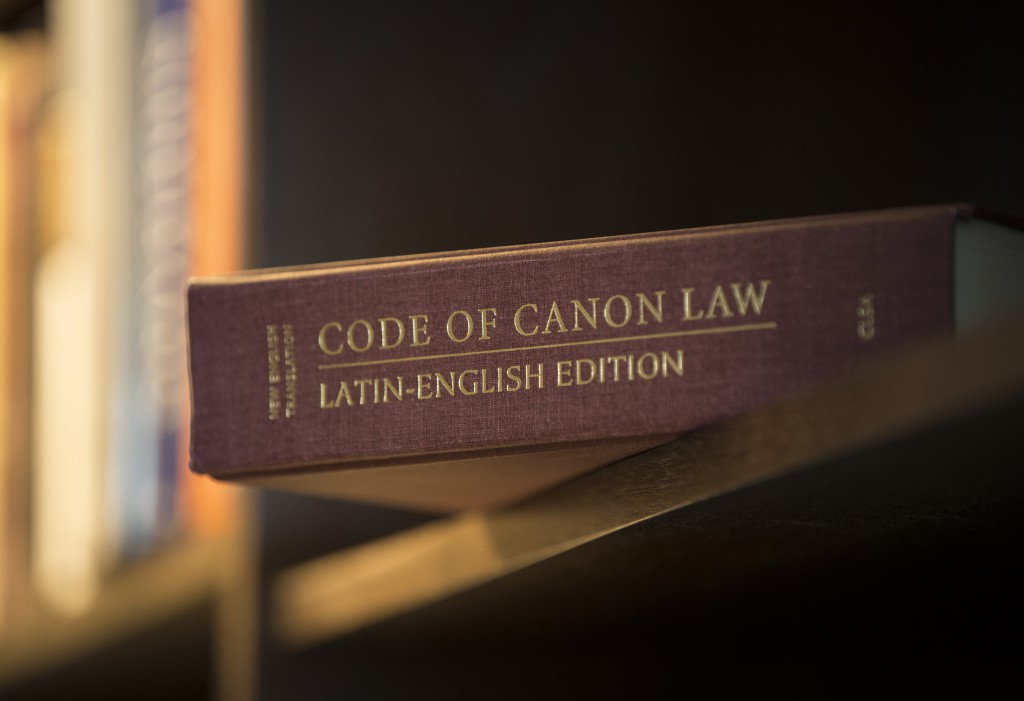 A Latin-English edition of the Code of Canon Law is pictured on a bookshelf. The Pontifical Council for Legislative Texts is drafting text for a new “Book VI: Sanctions in the Church” section of the code dealing with offenses and penalties. PHOTO: CNS