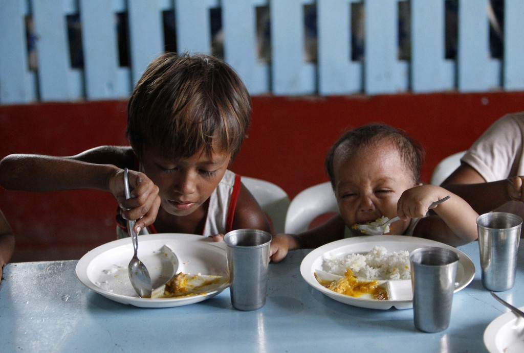 A boy and his younger brother eat their free meals May 22 during a feeding program at a slum area in Manila, Philippines. Archbishop Francis A. Chullikatt, permanent observer of the Holy See to the United Nations, told a U.N. General Assembly meeting May 23 that it was urgent to resolve the "ongoing scandal" of hunger in today's world.  PHOTO: CNS/Romeo Ranoco, Reuters