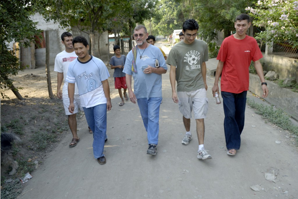 Maryknoll Father Thomas Goekler, at center in the blue shirt, walks through the streets of Chamelecon, Honduras, in early May, 2007 with young men he is keeping out of violent gangs. PHOTO: CNS/Paul Jeffrey