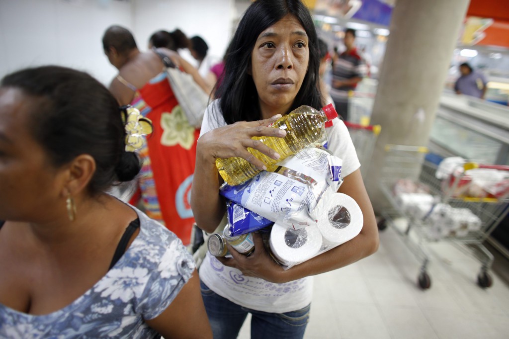 A woman carries products at a state-run supermarket in Caracas, Venezuela, June 4. Sporadic shortages of basic goods in the country can turn a roll of toilet paper into a rare commodity. Clergy and religious are worried about running low on altar wine and wheat to make hosts. PHOTO: CNS/Jorge Silva, Reuters