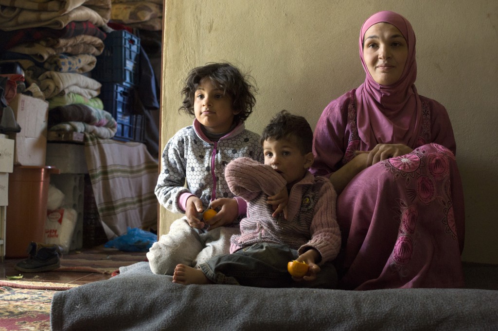 A Syrian mother and her two children are pictured in their new home on a farm in Bekaa Valley outside of Beirut, Lebanon, in March. In exchange for lodging they tend cattle -- a far cry from their former life in Damascus. PHOTO: CNS/Peter Balleis, S.J., Jesuit Refugee Service