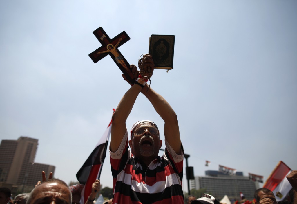 A protester, who opposes former Egyptian President Mohammed Morsi, holds up a copy of the Quran and a cross during a rally at Cairo's Tahrir Square July 5. Egypt's Catholic leaders welcomed the ouster of the Islamist president and pledged to help "rebuild democracy" under army rule. PHOTO: CNS/Khaled Abdullah, Reuters