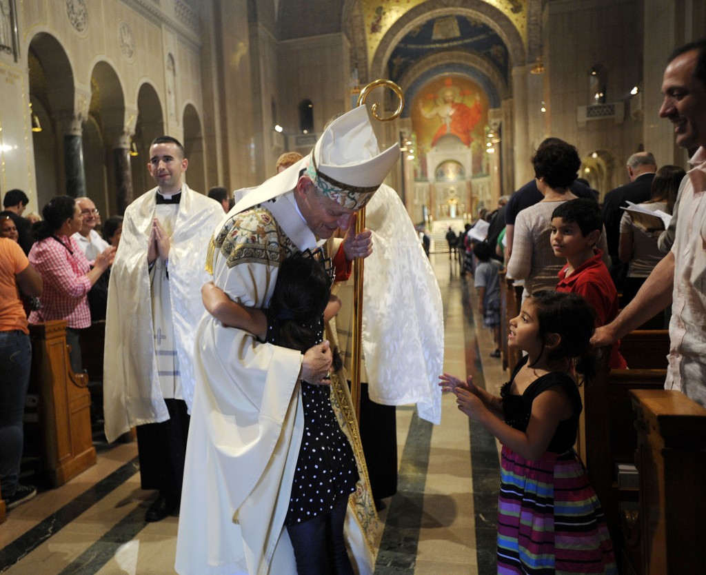 A young girl embraces Cardinal Donald W. Wuerl of Washington during the recessional of the Fortnight for Freedom closing Mass at the Basilica of the National Shrine of the Immaculate Conception in Washington July 4. The campaign, initiated by the U.S. bishops in 2012, is a two-week period of prayer, education and action on preserving religious freedom in the U.S. PHOTO: CNS/Leslie E. Kossoff
