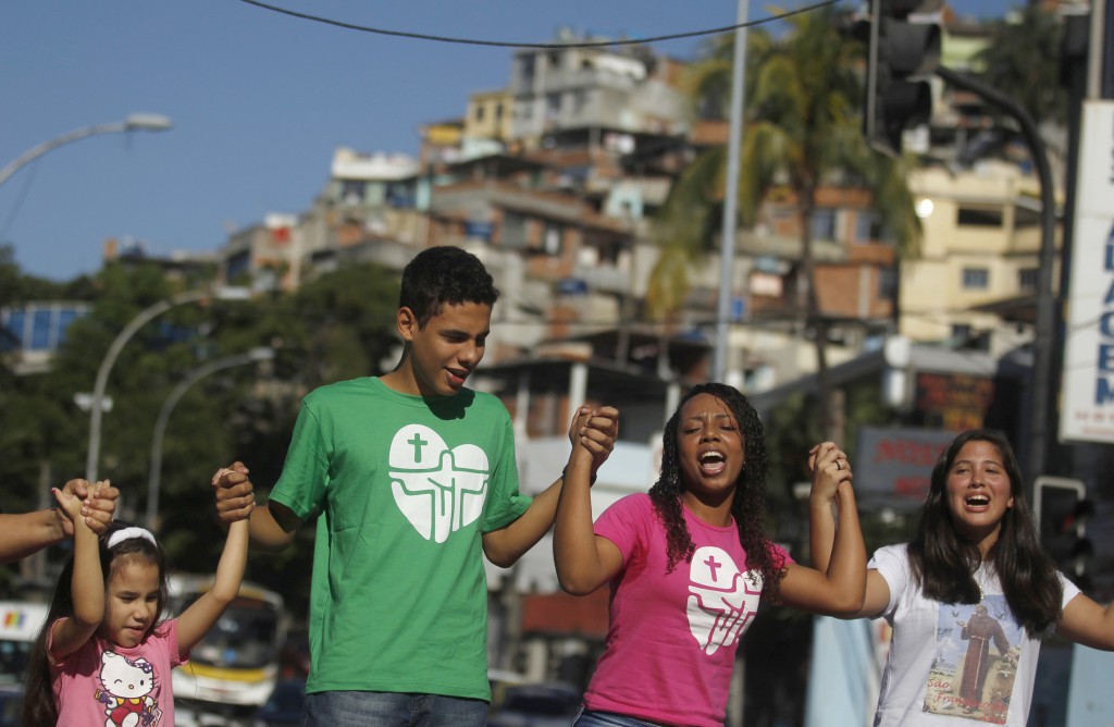 Young people sing and dance before the arrival of the World Youth Day cross and icon at the Vidigal slum on July 15 in Rio de Janeiro. PHOTO: CNS/Pilar Olivares, Reuters