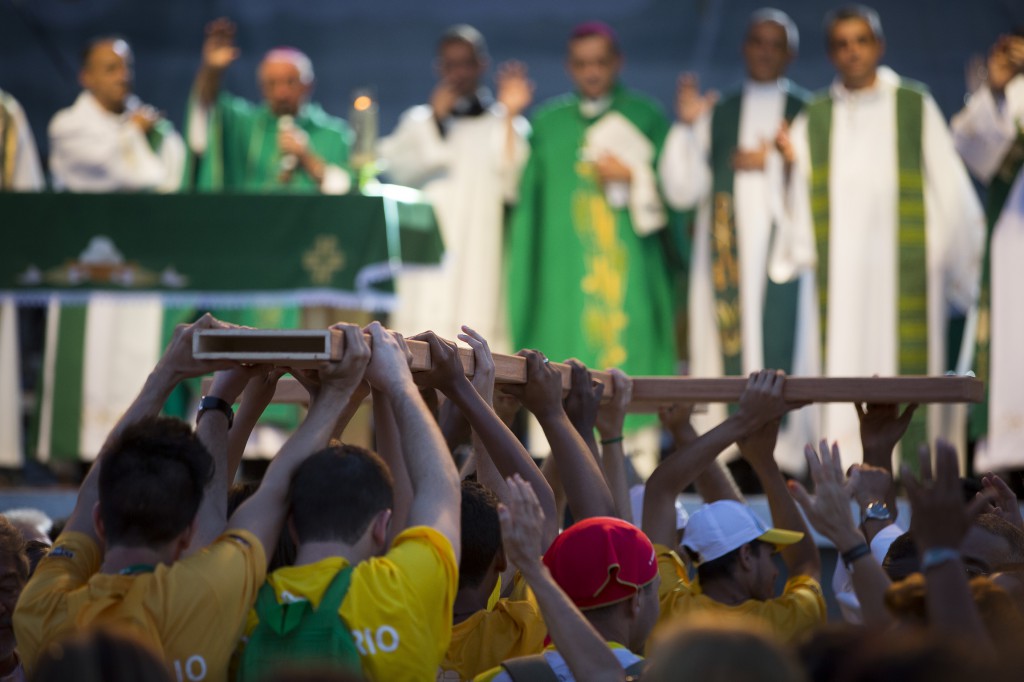 Pilgrims carry a cross to the altar during a Mass at the close of World Youth Day's missionary week on July 21 in Nilopolis, Brazil.