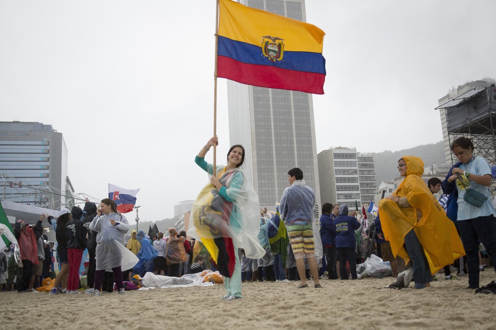 A pilgrim form Ecuador holds her country's flag on Copacabana beach as young people gathering for the World Youth Day opening Mass July 23 in Rio de Janeiro. PHOTO: CNS/Tyler Orsburn