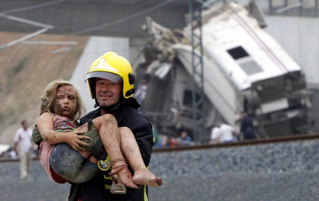 A fireman carries an injured girl from the wreckage of a train crash July 24 in Galicia, Spain, near the pilgrimage site of Santiago de Compostela. At least 80 people died and more than 100 others were injured when the train derailed, the president of the regional government said. PHOTO: CNS/Xoan A. Soler/Monica Ferreiros/La Voz de Galicia via Reuters