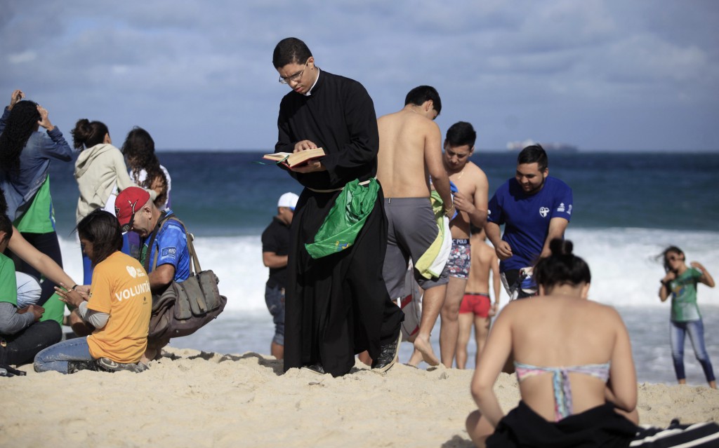 A priest reads the Bible on July 26 as he waits for the arrival of Pope Francis on Copacabana beach during World Youth Day in Rio de Janeiro. PHOTO: CNS/Ricardo Moraes, Reuters