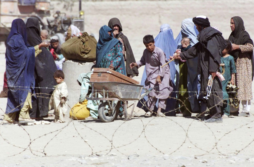 A Taliban fighter speaks to Afghan refugees waiting to cross into Pakistan at the Chaman border crossing in 2001. PHOTO: CNS/Reuters