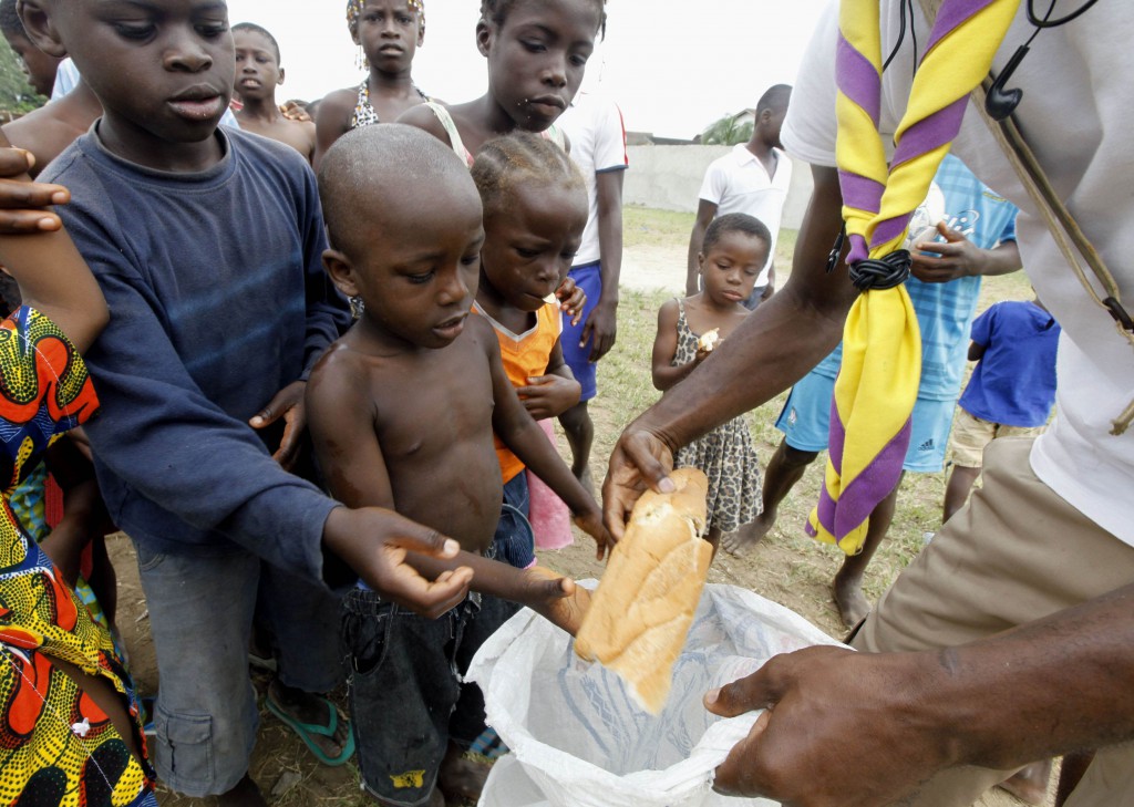 A man distributes bread to children at St. Ambrose Church in Abobo, Ivory Coast, March 1. Located just north of the capital of Abidjan, the church has served as a temporary refuge for people fleeing political violence. PHOTO: CNS/Thierry Gouegnon, Reuters