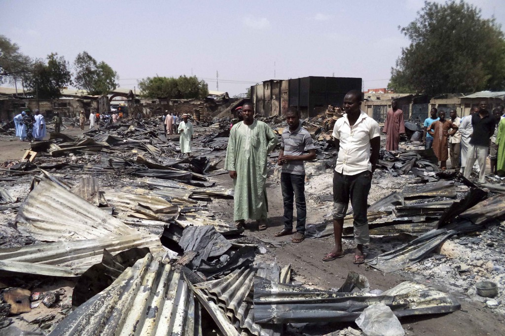 People gather around the ruins of the burned Bama Market in Maiduguri, Nigeria, April 29, after it was destroyed by gunmen. PHOTO: CNS/Afolabi Sotunde, Reuters