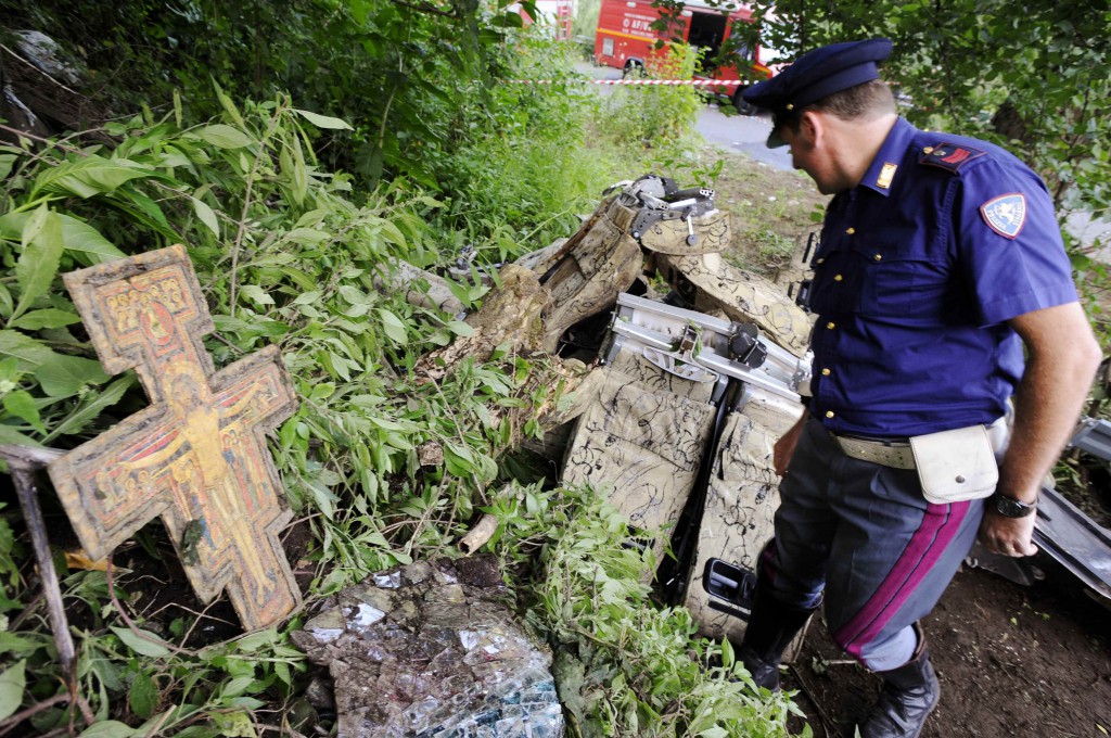 A crucifix is seen as a policeman surveys the wreckage of a bus that crashed near the town of Avellino in southern Italy July 29. At least 38 people died when the bus filled with pilgrims returning from a Catholic shrine tour plunged off an elevated highway. PHOTO: CNS/Ciro De Luca, Reuters