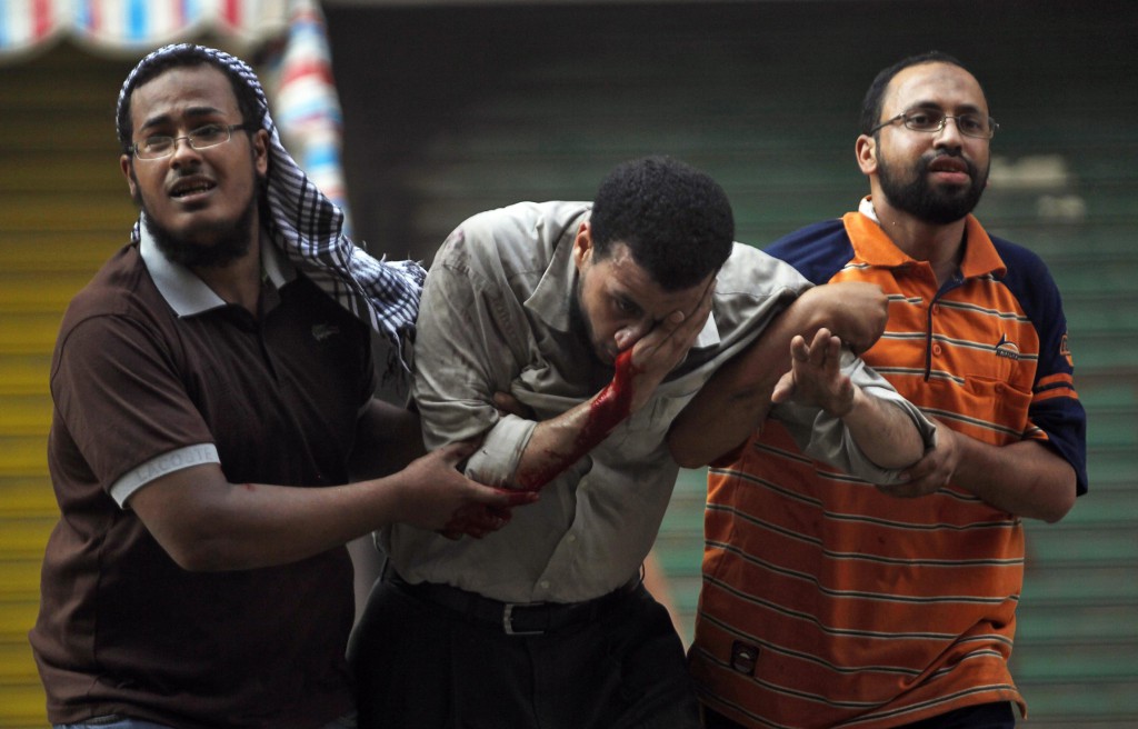 Protesters who support ousted Egyptian President Mohammed Morsi assist an injured demonstrator during clashes outside a police station in Cairo Aug. 16. A prominent Egyptian bishop said his country will not have a civil war, and international bodies should not intervene. PHOTO: CNS/Amr Abdallah Dalsh, Reuters