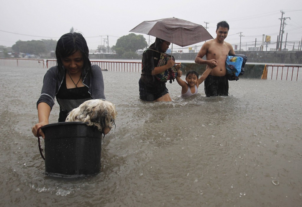 Residents in Paranaque city wade in waist-deep floodwaters in metro Manila, Philippines, Aug. 20. Heavy rains continue to batter the Philippine capital and nearby provinces, causing government offices, schools and some businesses to suspend work. Thousands of people had to leave their homes. PHOTO: CNS/Romeo Ranoco, Reuters