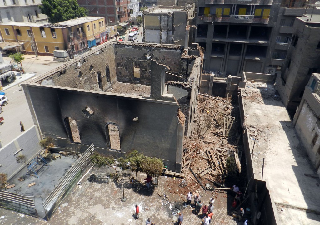 People walk around a destroyed Protestant church in Mallawi, Egypt, Aug. 17. Christians, making up 10 percent of Egypt's 85 million people, have coexisted with the majority Sunni Muslims for centuries. Violence erupted periodically, especially in the impoverished South, but the attacks on churches and Christian properties in the last week were the worst in years. PHOTO: CNS/Reuters