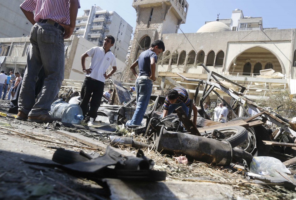 Relatives of car bomb victims inspect the damaged cars at the explosion site in front of a mosque in Tripoli, Lebanon, Aug. 24. Bombs hit two mosques the day before in the northern Lebanese port city, killing dozens of people and wounding hundreds. PHOTO: CNS/Jamal Saidi, Reuters