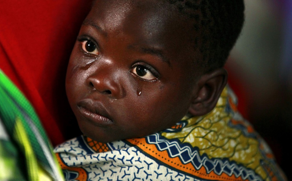 A boy, displaced by recent fighting between Congolese army and the M23 rebels, is held during a Sunday church service in Munigi village near Goma Sept. 1. Bishop Willy Ngumbi Ngengele of Kindu said many communities in the area continue to suffer from the strikes committed by the M23 rebels. PHOTO: CNS/Thomas Mukoya, Reuters