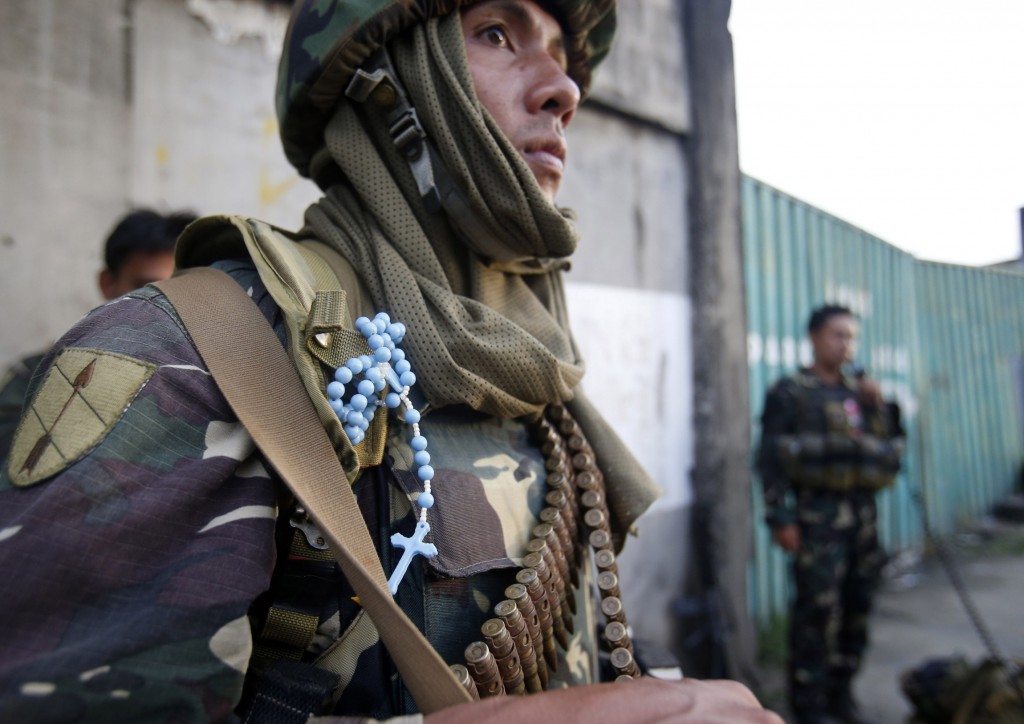 A rosary is seen on the uniform of a government soldier as he guards a road in downtown Zamboanga, Philippines, Sept. 10. Houses were set ablaze on that day as fighting erupted between Philippine security forces and Muslim rebels occupying five districts of the southern Philippine city. PHOTO: CNS/Erik De Castro, Reuters