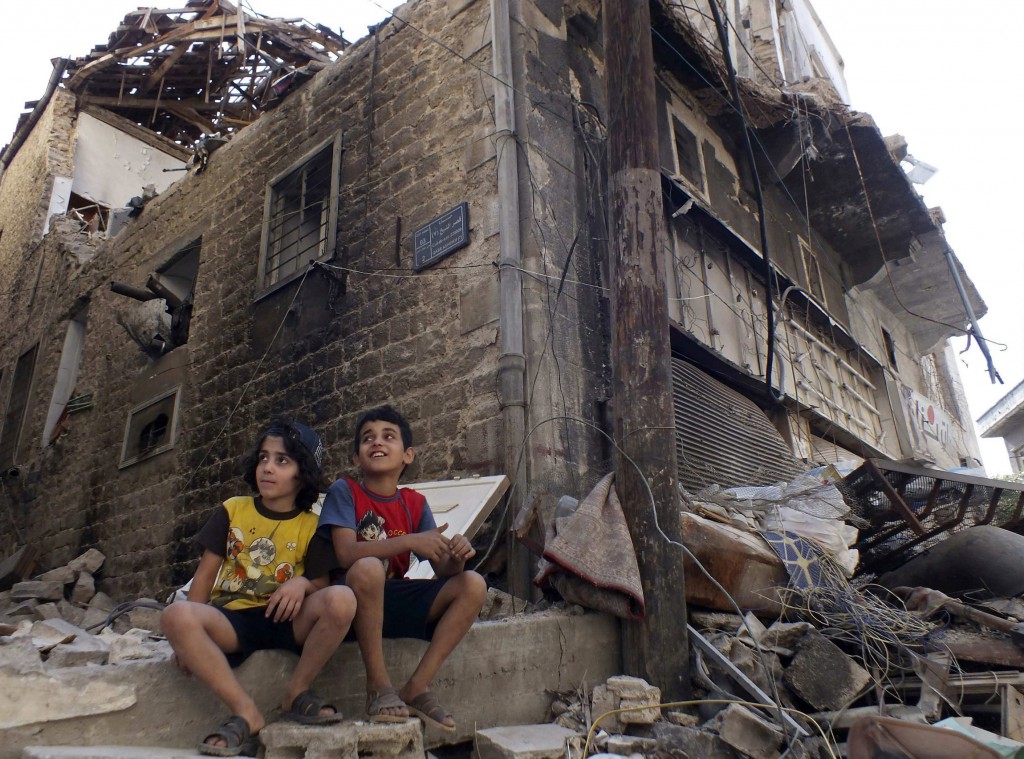 Children sit along a damaged street filled with debris in the besieged area of Homs, Syria, Sept. 19. Two bombings a day later killed at least 39 people in the latest surge in violence. PHOTO: CNS/Yazan Homsy, Reuters