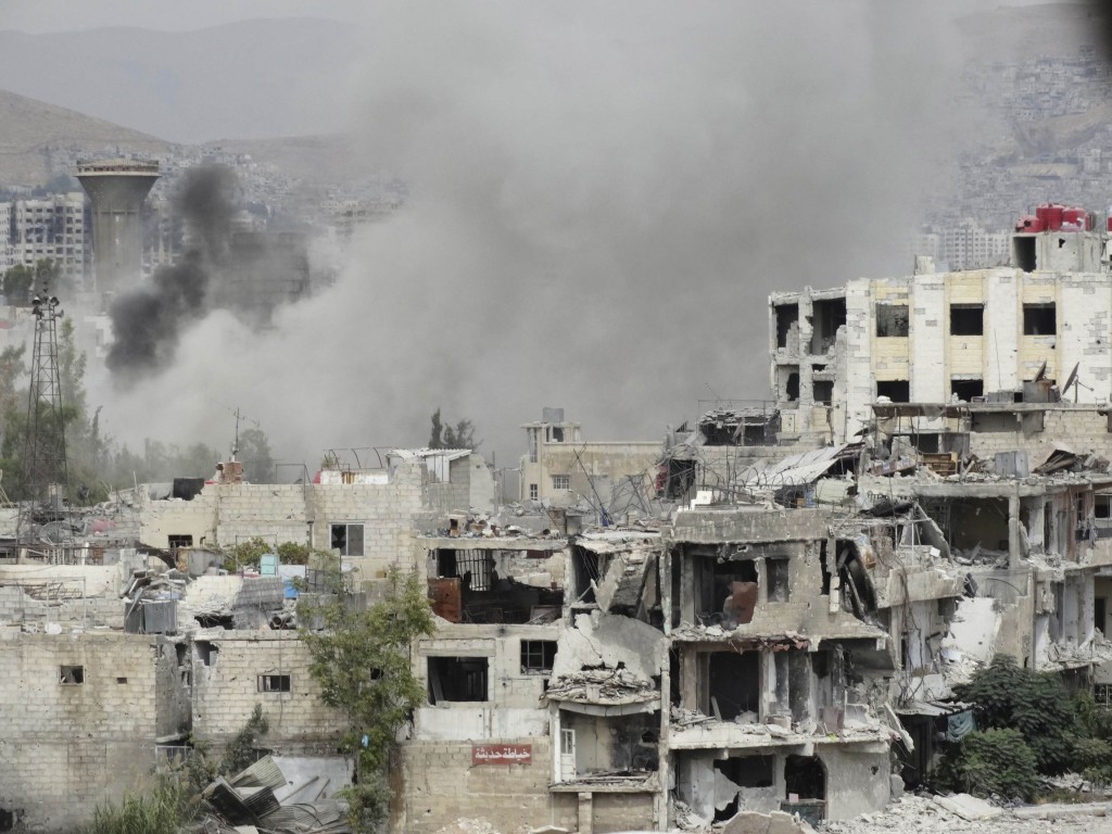 Smoke rises from behind a building in Damascus, Syria, Sept. 18. Two bombings a day later killed at least 39 people in the latest surge in violence. PHOTO: CNS/Msallam Abd Albaset, Reuters