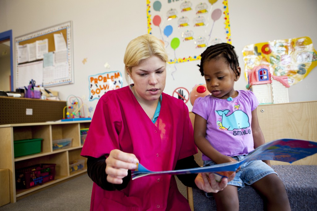 A teaching assistant reads with a girl at the Baltimore Catholic Charities Head Start program in Edgewood, Md., in this June 13 file photo. Although the Edgewood program remains open, other Head Start sites have felt the effects of the government funding crisis and budget cuts, impacting nearly 19,000 children across the nation. PHOTO: CNS/Nancy Phelan Wiechec