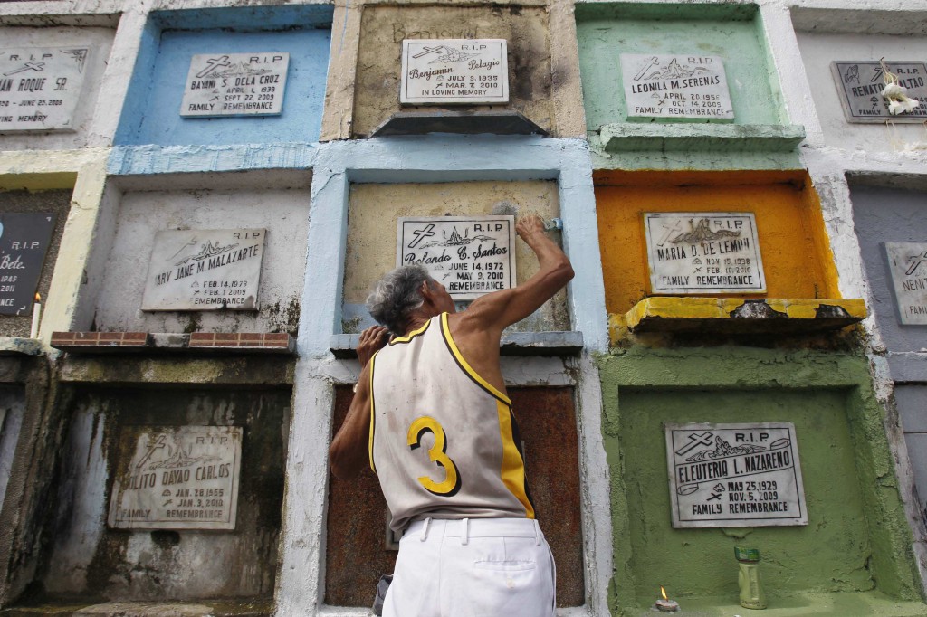 A man applies paint on his relative's  tomb at a public cemetery in Manila Oct. 31, 2012, in preparation for All Saints' Day Nov. 1 and All Souls' Day Nov. 2. In the Philippines, putting a fresh coat of paint on a grave site is one of the most common ways to honor the dead in one's family. PHOTO: CNS/Romeo Ranoco, Reuters
