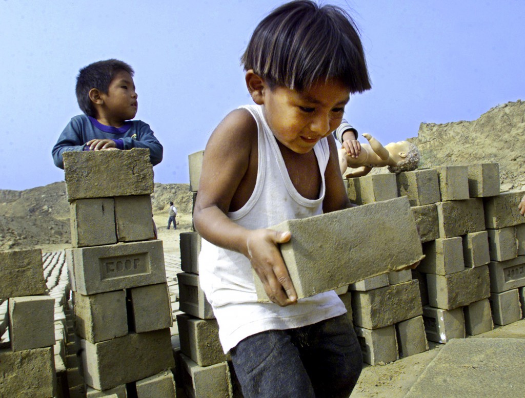 Three-year-old Victor Garcia moves a brick at a brickyard in a Lima, Peru, shantytown June 15. The National Statistics Institute in Peru reported in 2002 that 1.8 million children ages 6 to 17 do some form of work in the country, from tending cattle in rural areas to washing windshields in the most modern parts of Lima. PHOTO: CNS from Reuters