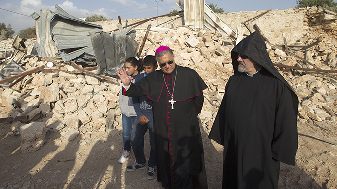 Children look on as Latin Patriarch of Jerusalem Fouad Twal (C) stands amongst the ruins of a Palestinian home, on November 5, 2013. PHOTO: AFP/Ahmad Gharabli