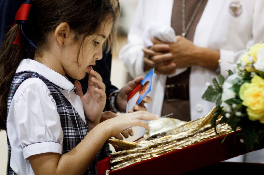 A student from St. Hugh Catholic School in Miami holds a prayer card over a relic of Blessed John Paul II, a specimen of his blood, during a Nov. 5 youth rally in honor of the future saint at St. Thomas University in Miami. The rally was part of a Nov. 3-21 tour that gave Catholics at some 10 parishes in the Miami Archdiocese a chance to view and venerate the relic of the late pope.  PHOTO: CNS/Tom Tracy