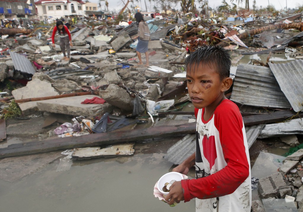 A boy with a wound on his eye gathers coins and other salvageable materials with others from the ruins of houses on November 10 after Super Typhoon Haiyan battered Tacloban, Philippines. The typhoon, one of the strongest storms in history, is believed to have killed tens of thousands, but aid workers were still trying to reach remote areas.  Photo: CNS/Erik De Castro, Reuters