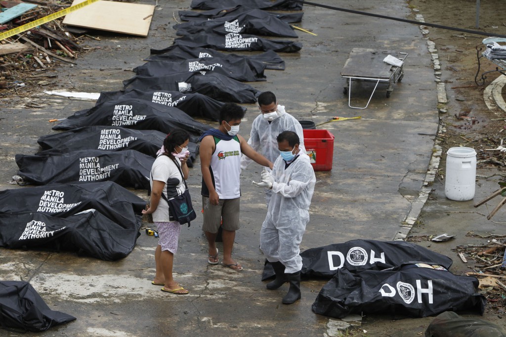 A man points at one of the bags containing bodies of typhoon victims Nov. 12 in Tacloban, Philippines, which was devastated by Super Typhoon Haiyan. Aid agencies faced challenges getting food and water to the hundreds of thousands of Filipinos affected by the storm. PHOTO: CNS/Romeo Ranoco, Reuters