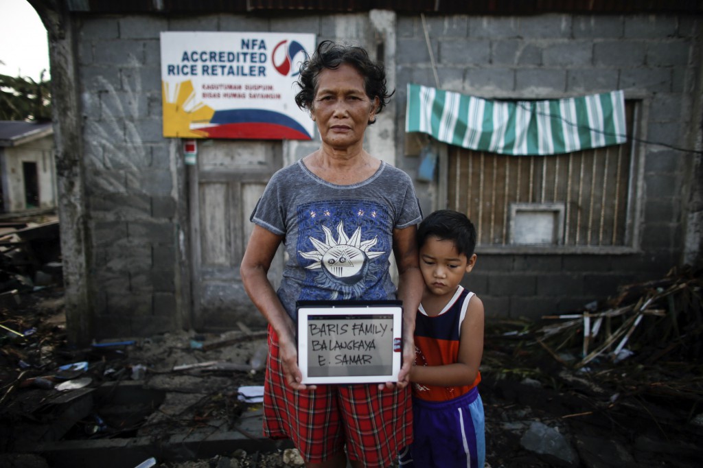 Typhoon Haiyan survivors pose with their names displayed on a tablet in Samar province in central Philippines Nov. 11. Photographer John Javellana was asked by several groups of Haiyan survivors to post their photos on social media sites so that loved ones would know they are alive. PHOTO: CNS/John Javellana, Reuters