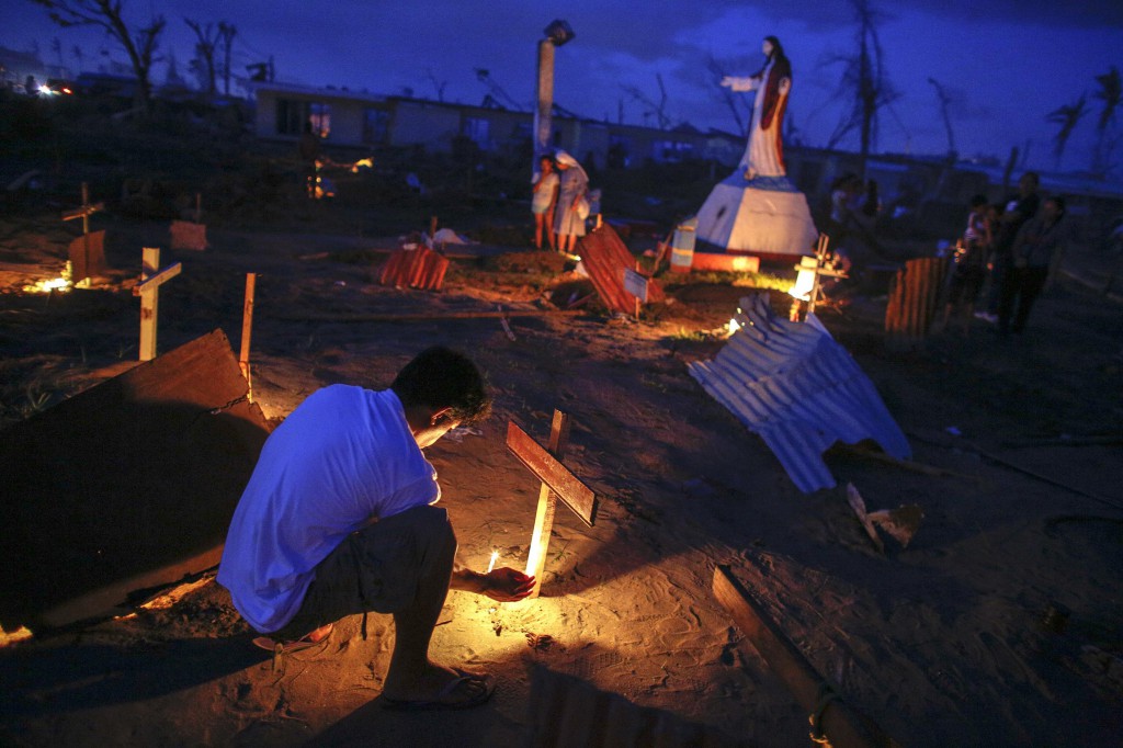 A man lights a candle Nov. 25 as he pays respects to a deceased relative at a mass grave where victims of Super Typhoon Haiyan are buried near St. Joaquin Church in the province of Leyte, Philippines. Haiyan, the most powerful storm to make landfall this year, struck the central Philippines Nov. 8, killing thousands and displacing more than 4 million people. PHOTO: CNS/Athit Perawongmetha, Reuters
