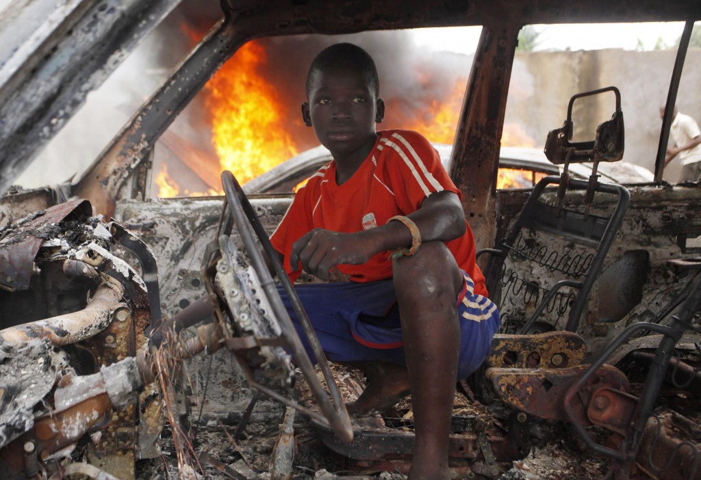 A youth squats inside a burned out car in Bangui, Central African Republic, Dec. 10. French troops in Bangui manned checkpoints in the capital and searched for weapons in an operation to disarm rival Muslim and Christian fighters responsible for hundreds of killings since early December. PHOTO: CNS/Emmanuel Braun, Reuters