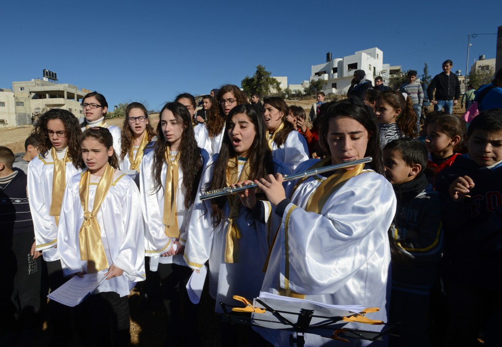 Young people from the Yasmeen Choir from the Magnificat Institute School for Music in Jerusalem perform on a field cleared of land mines in the West Bank village of Husan, near Bethlehem, Dec. 23. The mines were removed by deminers -- both Israeli and Palestinian -- from Roots of Peace in May. Roots of Peace has embarked on an international campaign to turn Mines to Vines in the Holy Land. PHOTO: CNS/Debbie Hill