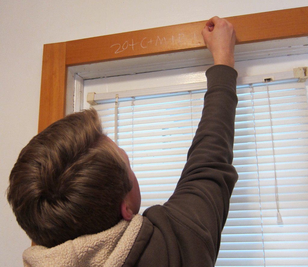 A man participating in a custom dating back to the Middle Ages, of writing a house blessing over a window or door frame.