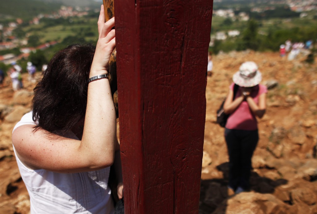 A woman prays against a crucifix on Apparition Hill in Medjugorje, Bosnia-Herzegovina, June 25. Millions of pilgrims from all over the world have visited the site where six village children first claimed to see Mary in June 1981. PHOTO: CNS/Dado Ruvic, Reuters